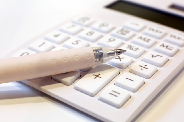 商標登録の費用を計算するための電卓と費用をメモするためのペン